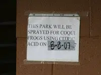 Sign that says This Park Will Be Sprayed for Frogs Using Citric Acid