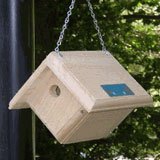 A wooden birdhouse hanging outdoors.