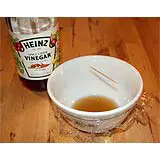 A bowl filled with vinegar with plastic wrap and a toothpick over it to illustrate the bowl fruit fly trap.
