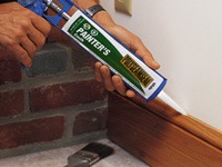 Hands caulking a sideboard.